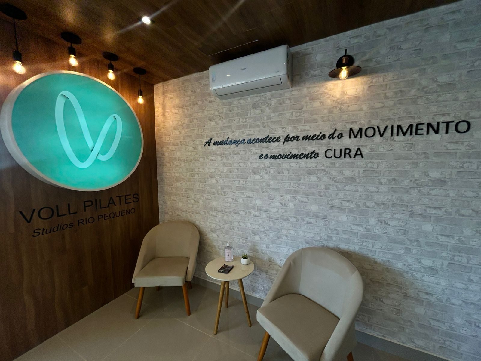 Recepção do Voll Pilates Rio Pequeno com o logo iluminado e a frase: a mudança acontece por meio do movimento
