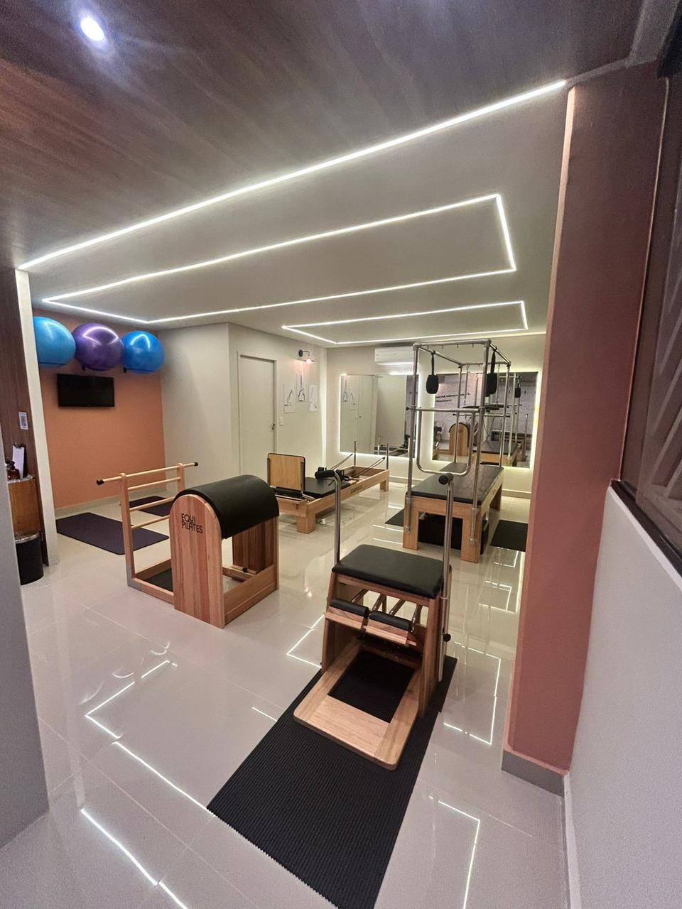 Vista geral do studio Voll Pilates Rio Pequeno com Reformer, Cadillac, Chair e Barrel e iluminação em LED